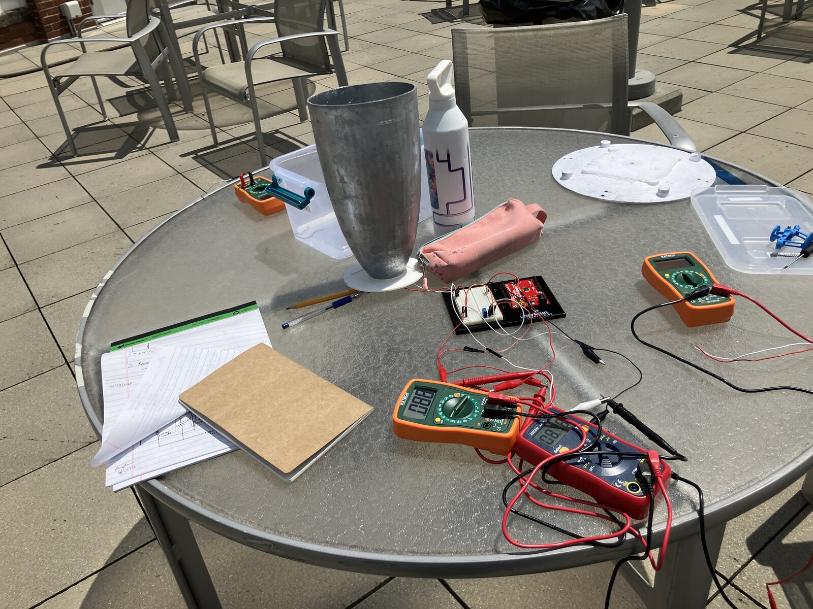 Outdoor testing on a patio table: the concentrator upright with multimeters and wiring